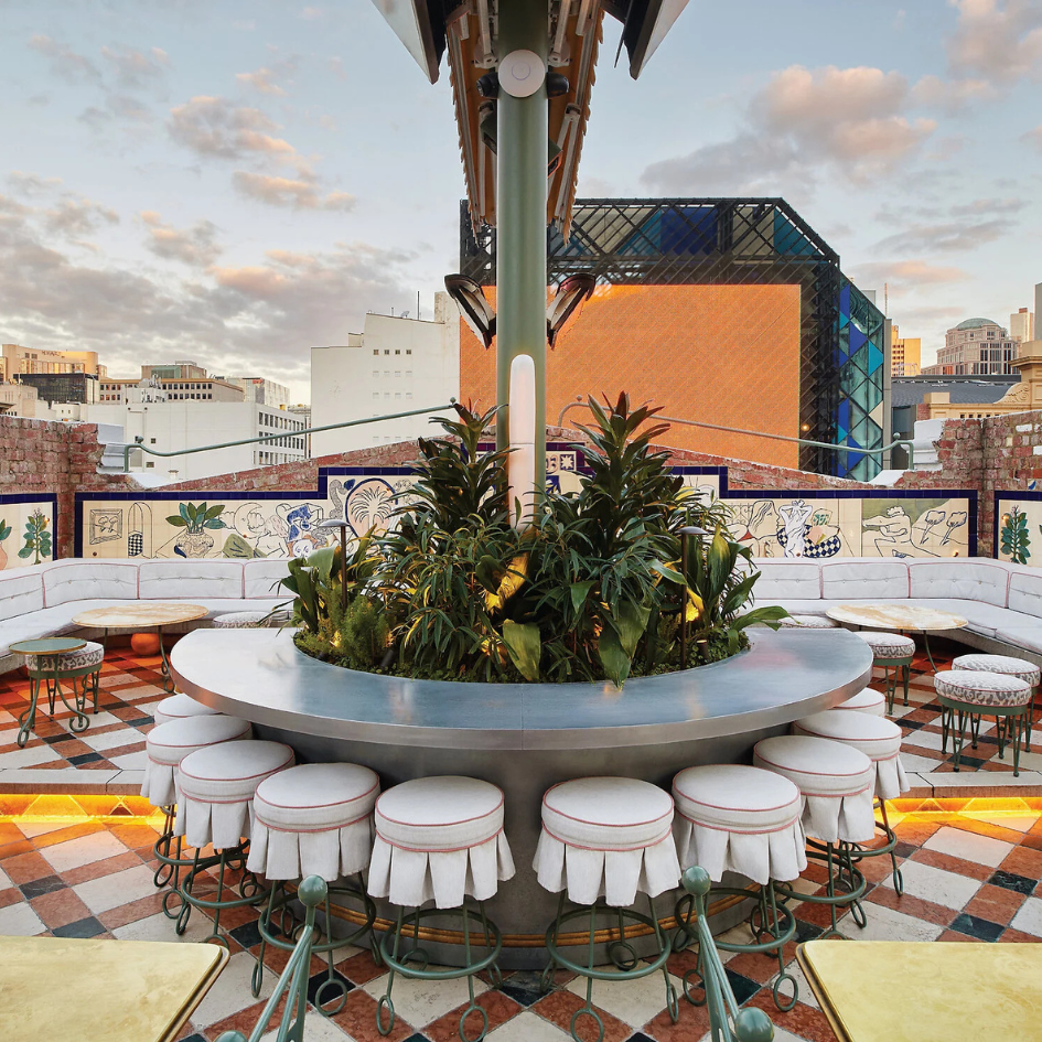 Rooftop bar overlooking buildings with circular bar with round stools