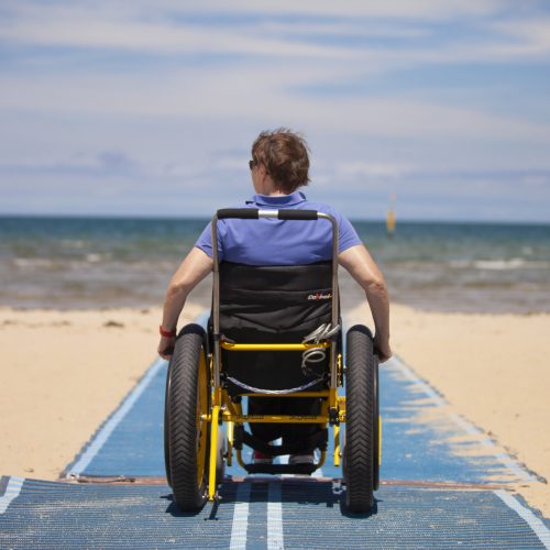 Wheelchair user on beach matting heading to the sea