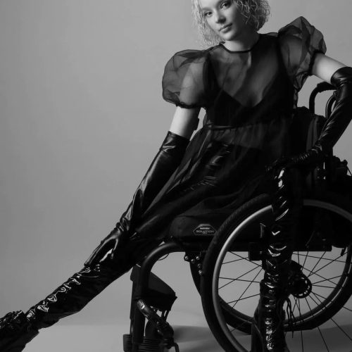 Black and white image of a girl in a black dress in a wheelchair.