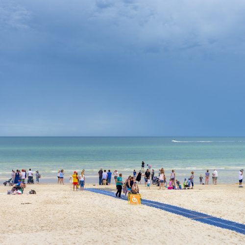 Wide shot of beach on sunny day with beach matting leading to water's edge