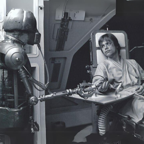 Black & white still from Star Wars with robot repairing Luke Skywalker's hand